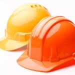 A pair of hard hats, yellow and orange, isolated on a white background